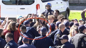 police officers in crowd of students; one officer has his baton raised over Sabrina Shirazi